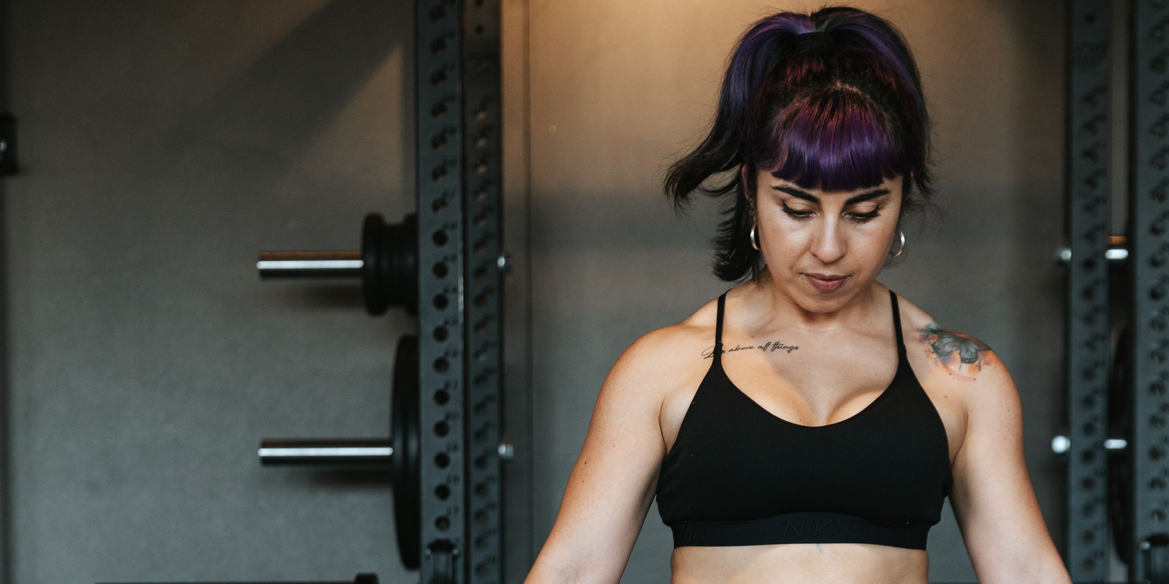 Romina setting up for a barbell lift in a squat rack